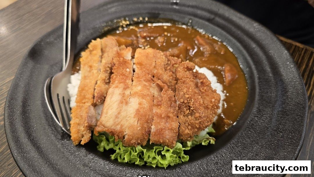 A close-up of a delicious Japanese curry with crispy fried chicken and rice.