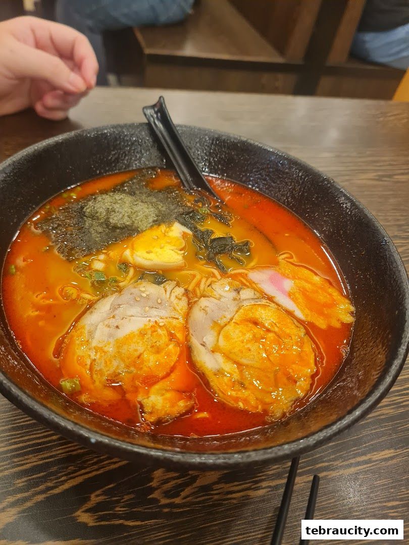 A close-up of a steaming bowl of ramen with pork, egg, seaweed, and broth.