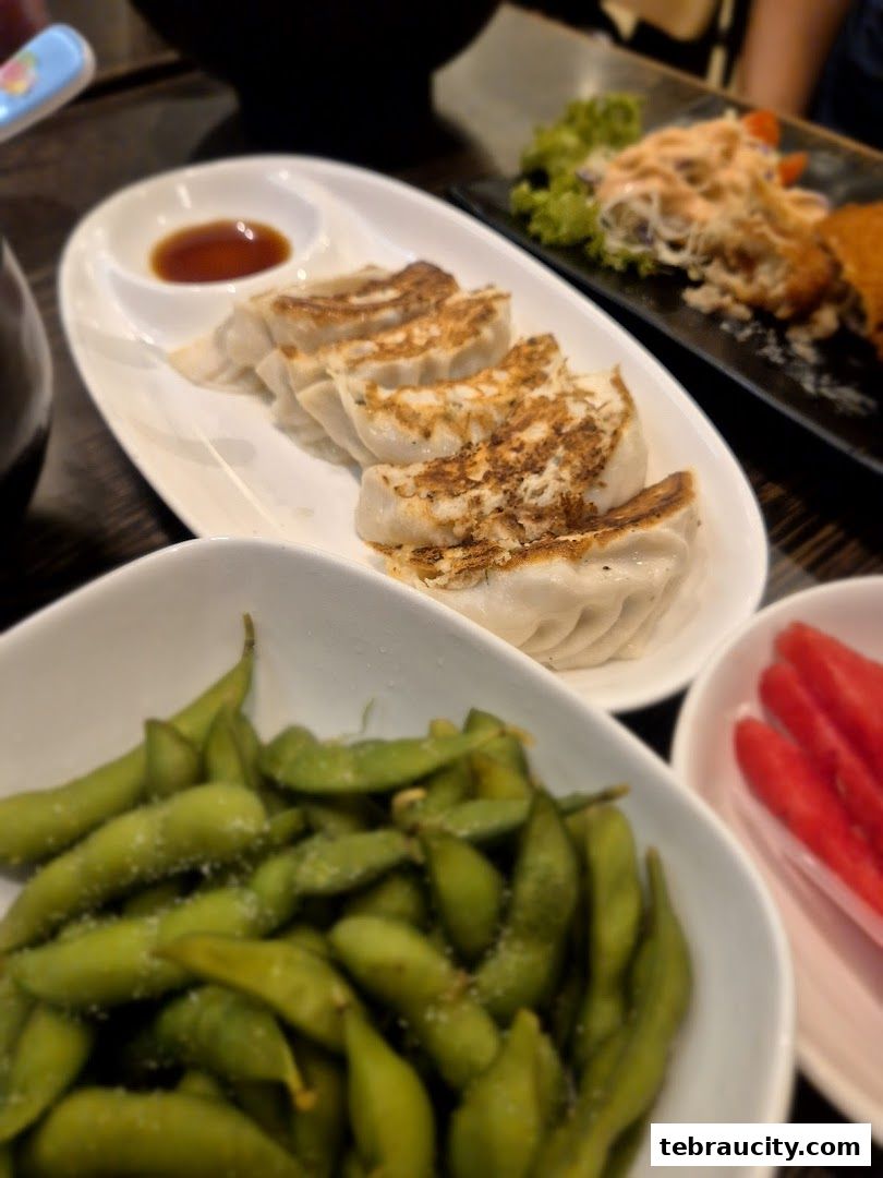 A close-up of delicious Japanese appetizers including gyoza, edamame, and what appears to be imitation crab sticks.