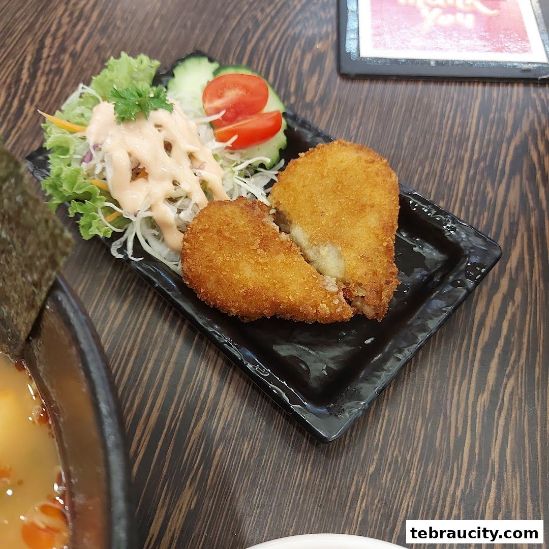 A plate of golden-brown fried croquettes served with a fresh salad and dressing.