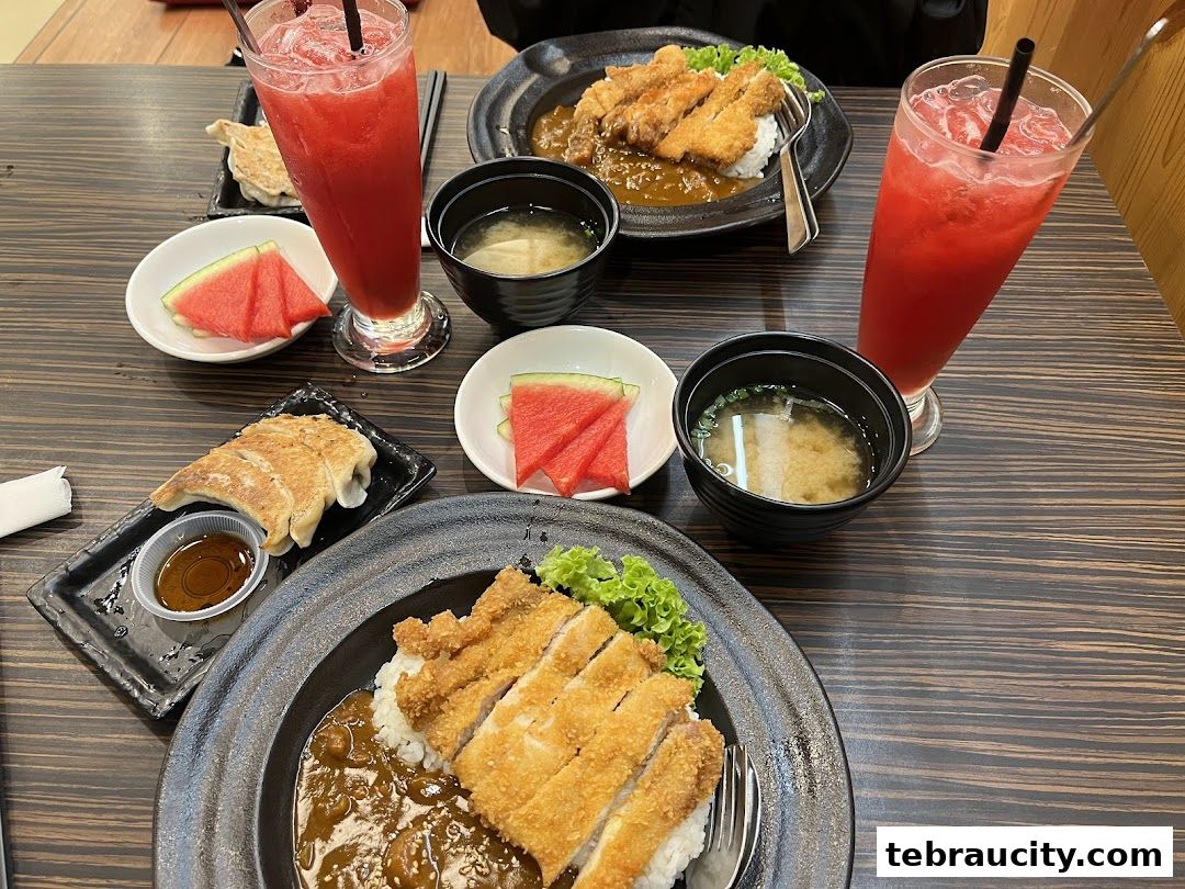 A table laden with Japanese dishes, including ramen, gyoza, and refreshing drinks.