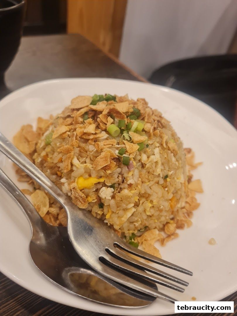 A close-up of a plate of fried rice topped with crispy fried shallots and green onions.