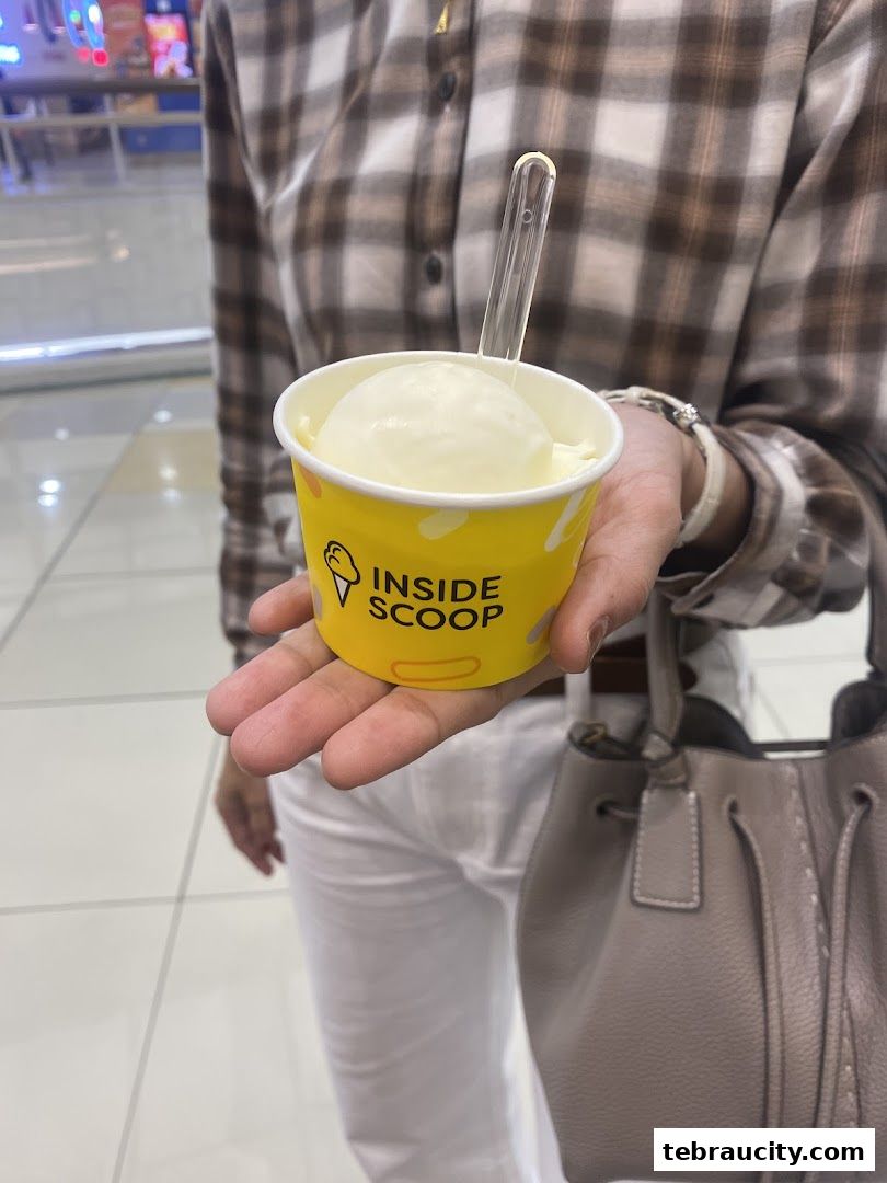 A person holds a cup of ice cream from Inside Scoop with a spoon.