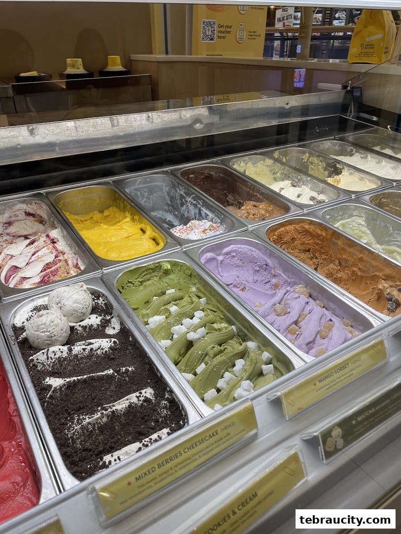 A display case filled with various flavors of ice cream, including mixed berries cheesecake and matcha.