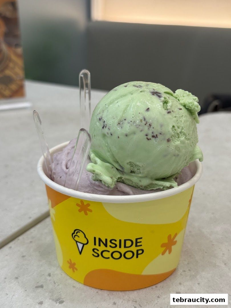 A cup of mint chocolate chip and purple ice cream with spoons.