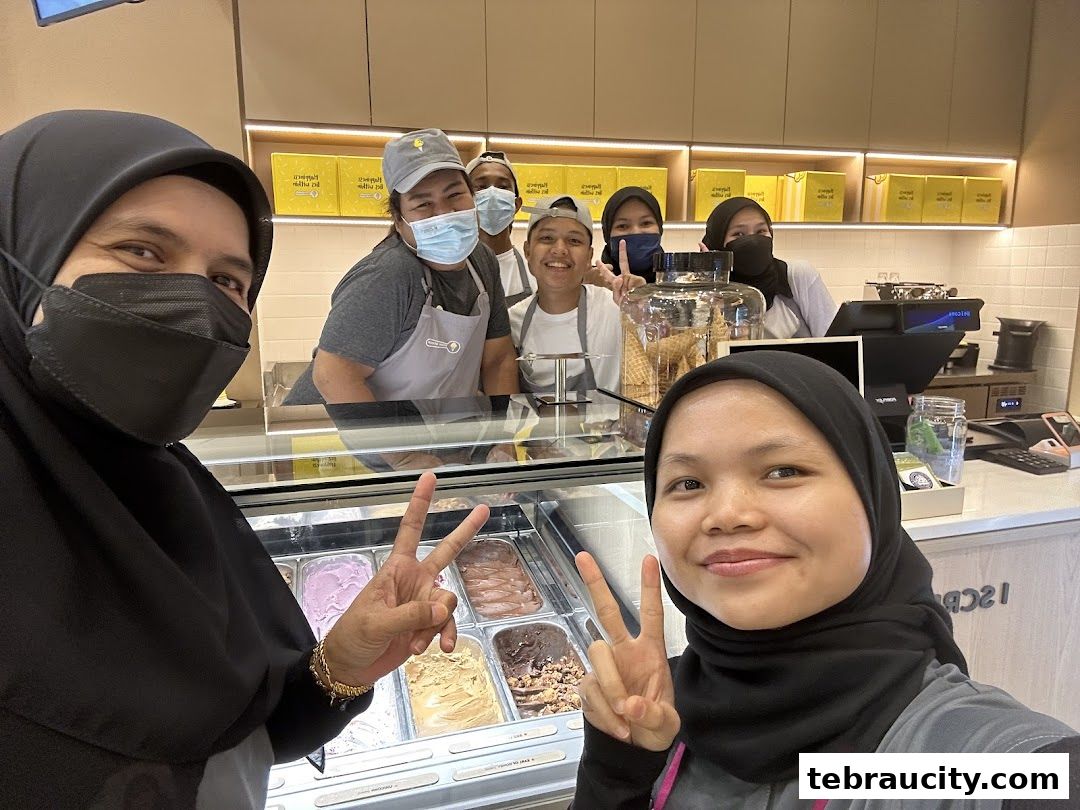 A group of smiling staff members pose for a selfie in front of an ice cream display.