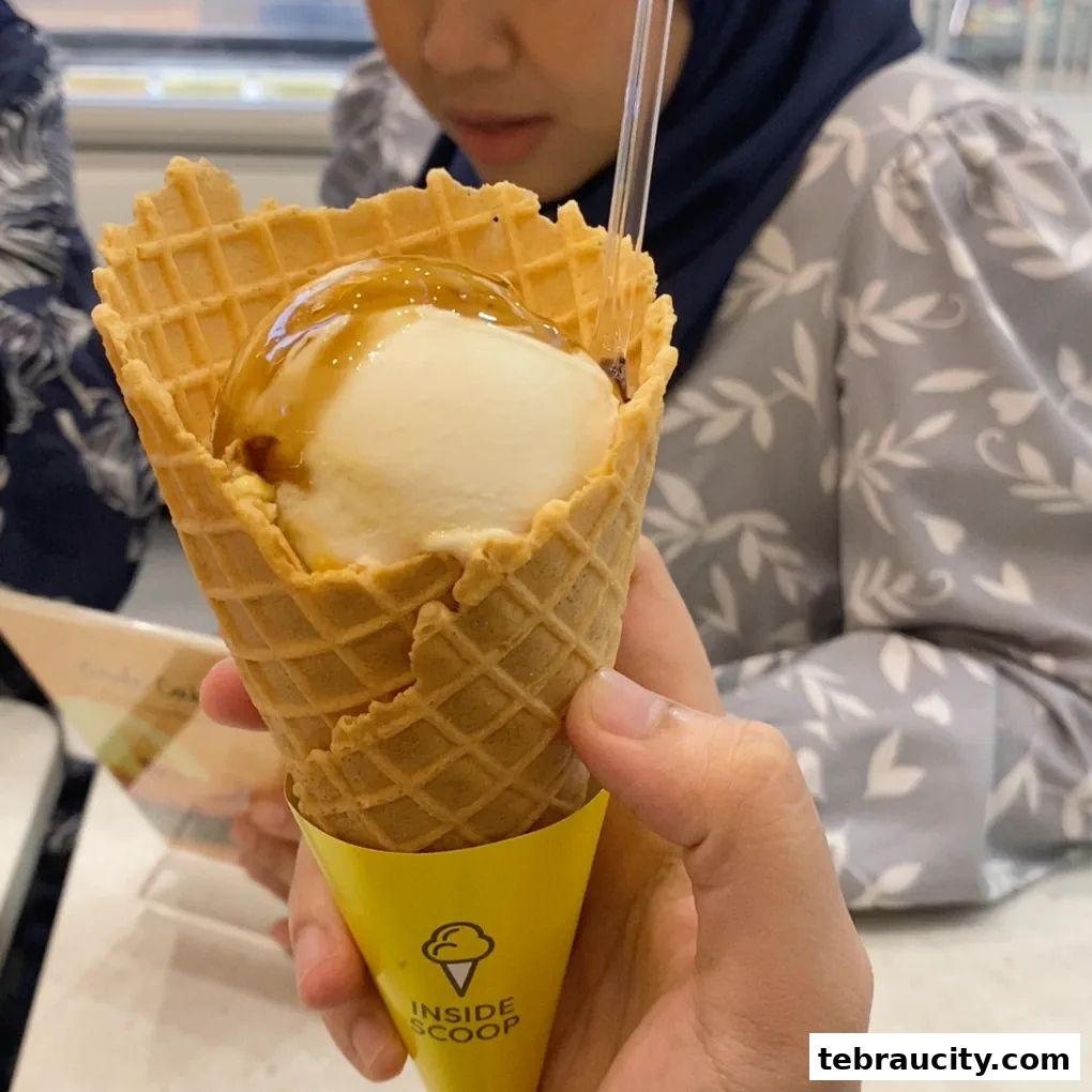 A hand holds an ice cream cone with caramel sauce and a waffle cone.
