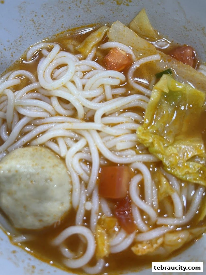 A close-up shot of a bowl of noodles with various ingredients in a savory broth.