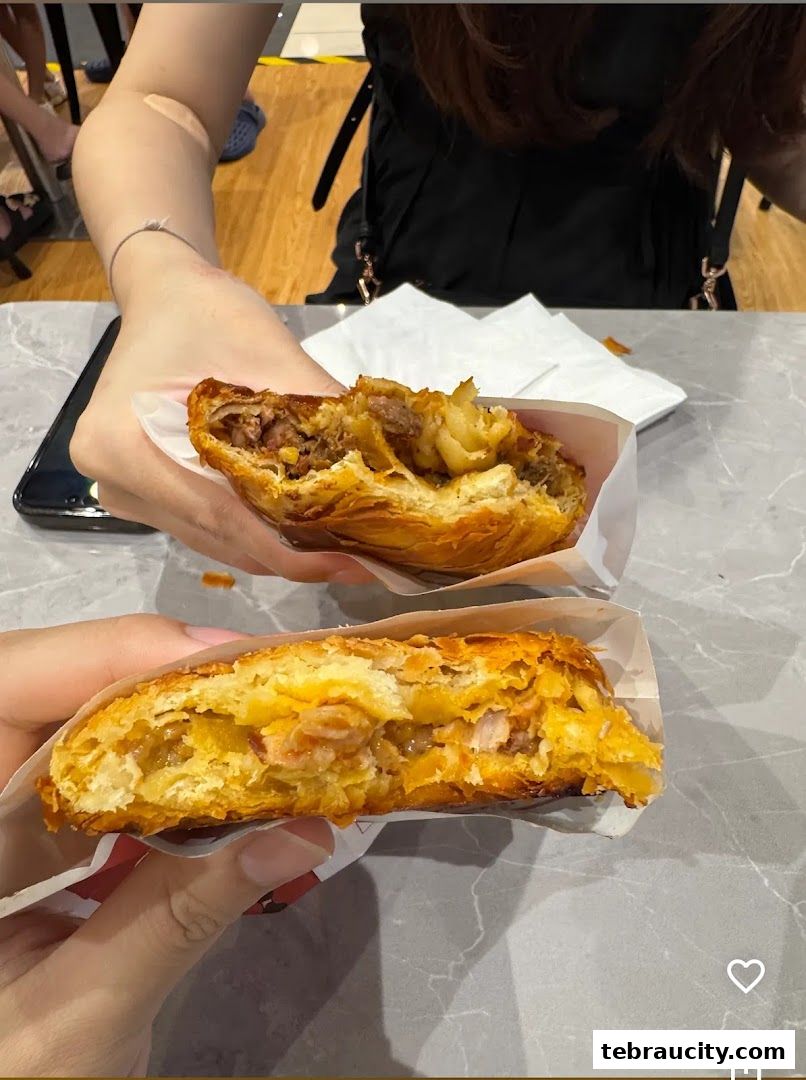 Two hands holding freshly baked, golden-brown scones filled with savory ingredients.