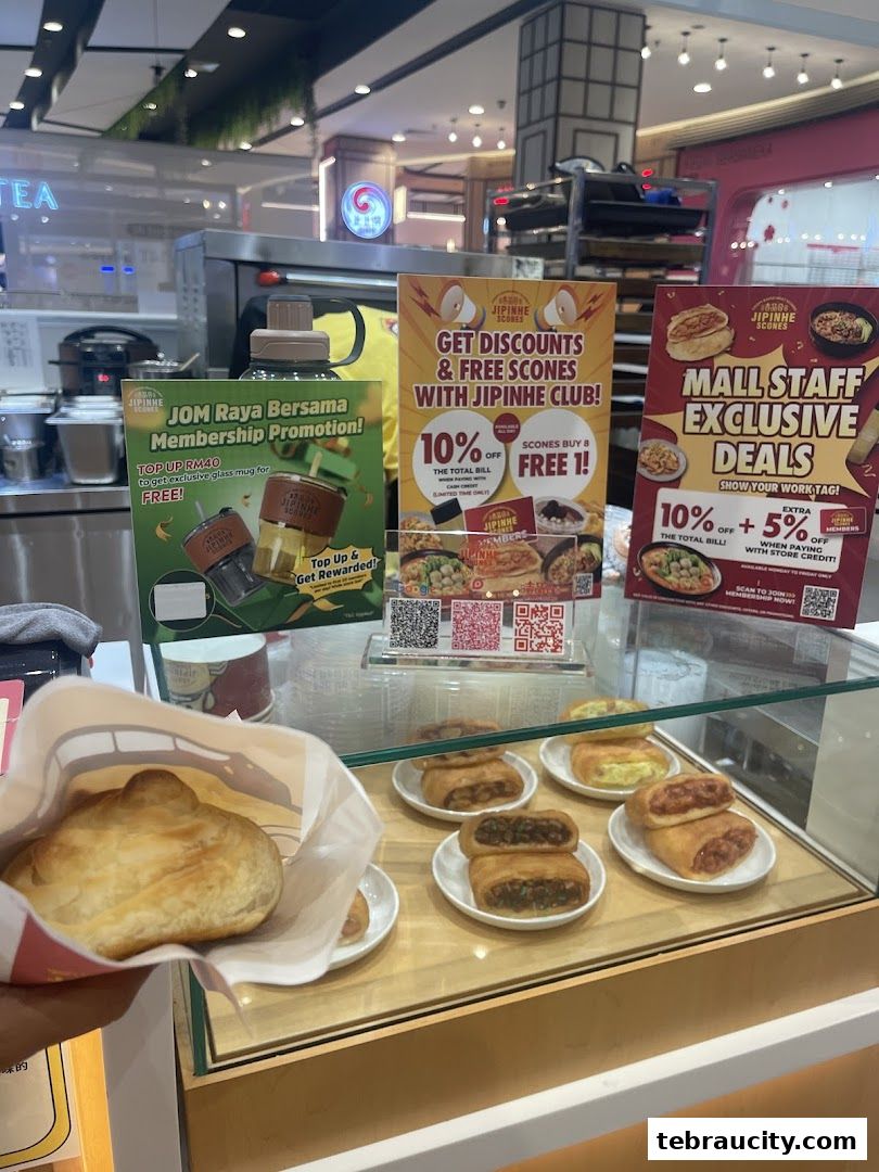 A display of Jipinhe scones with promotional posters and a hand holding a scone.