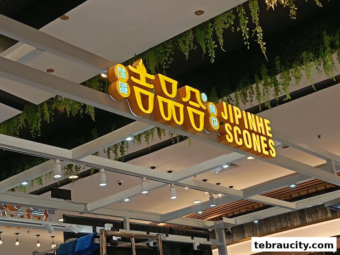 A brightly lit sign for Jipinhe Scones with decorative plants hanging above.