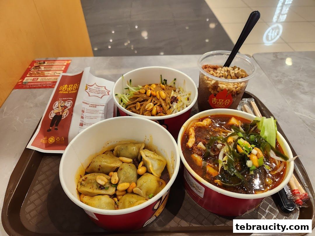 A tray of delicious Chinese food including dumplings, noodles, and a drink.