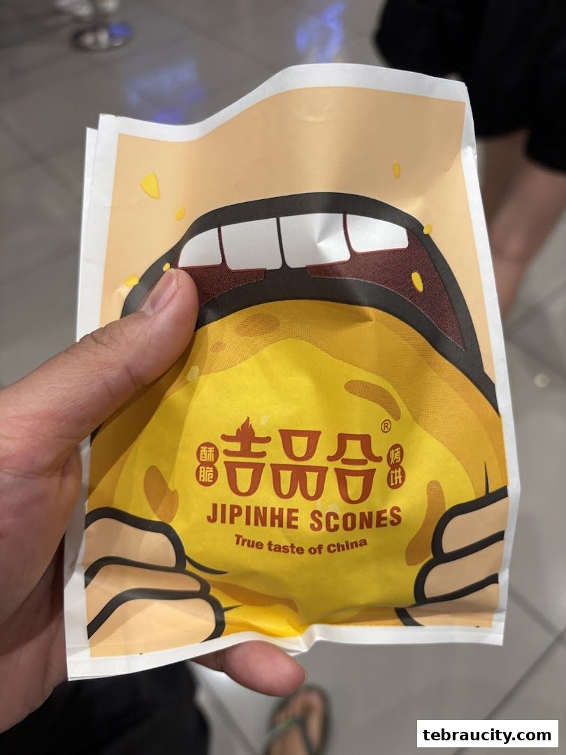 A hand holds a yellow scone packaging with a cartoon mouth design.