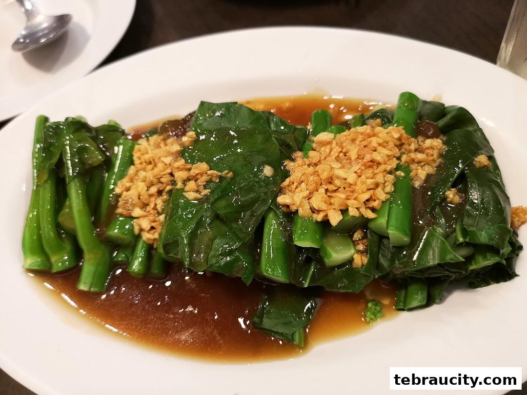 A plate of stir-fried Chinese broccoli with garlic and savory sauce.