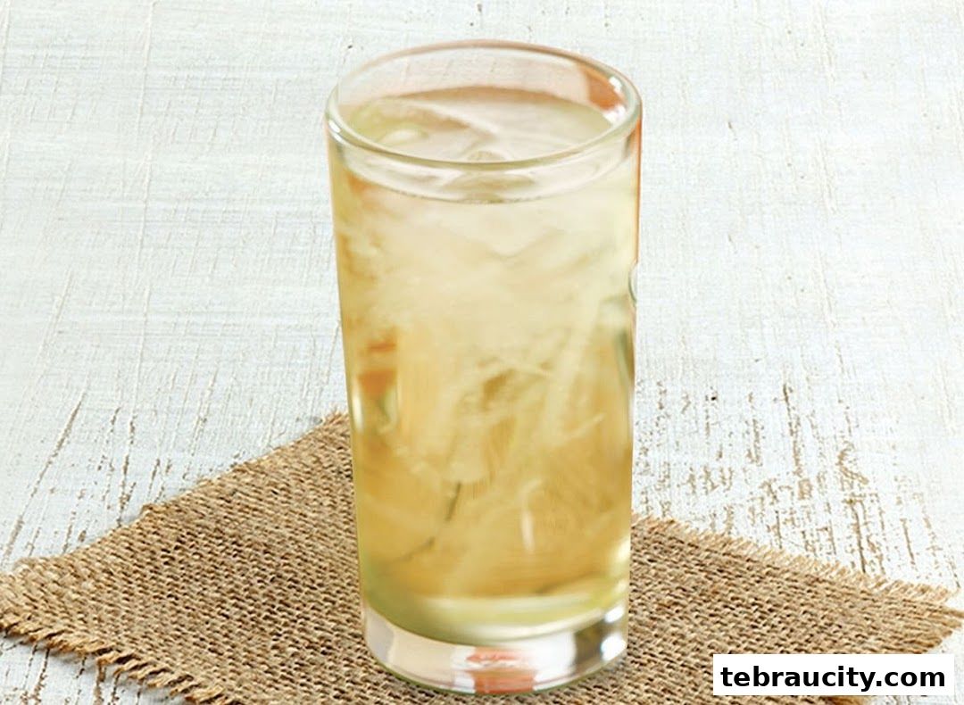 A tall glass of iced beverage with shredded ingredients on a burlap coaster.