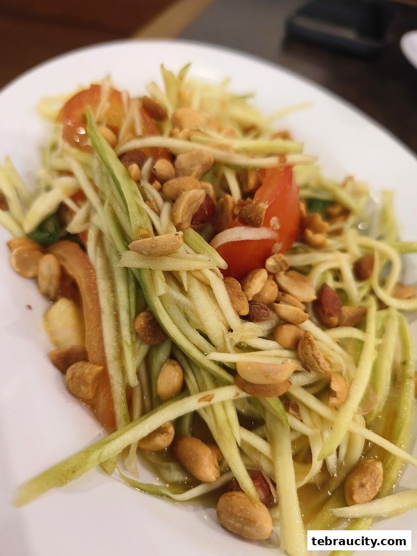 A close-up of a delicious green papaya salad with peanuts and tomatoes.