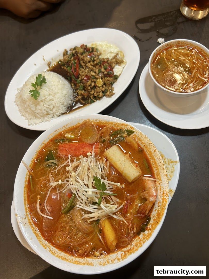 A close-up of three Thai dishes including Tom Yum soup, stir-fried minced meat with rice, and a noodle soup.