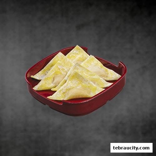 A red square plate holds several golden-yellow wontons against a dark background.