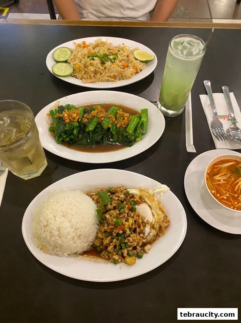 A table laden with delicious Thai dishes, including stir-fried rice, vegetables, and a hearty meat and rice meal.