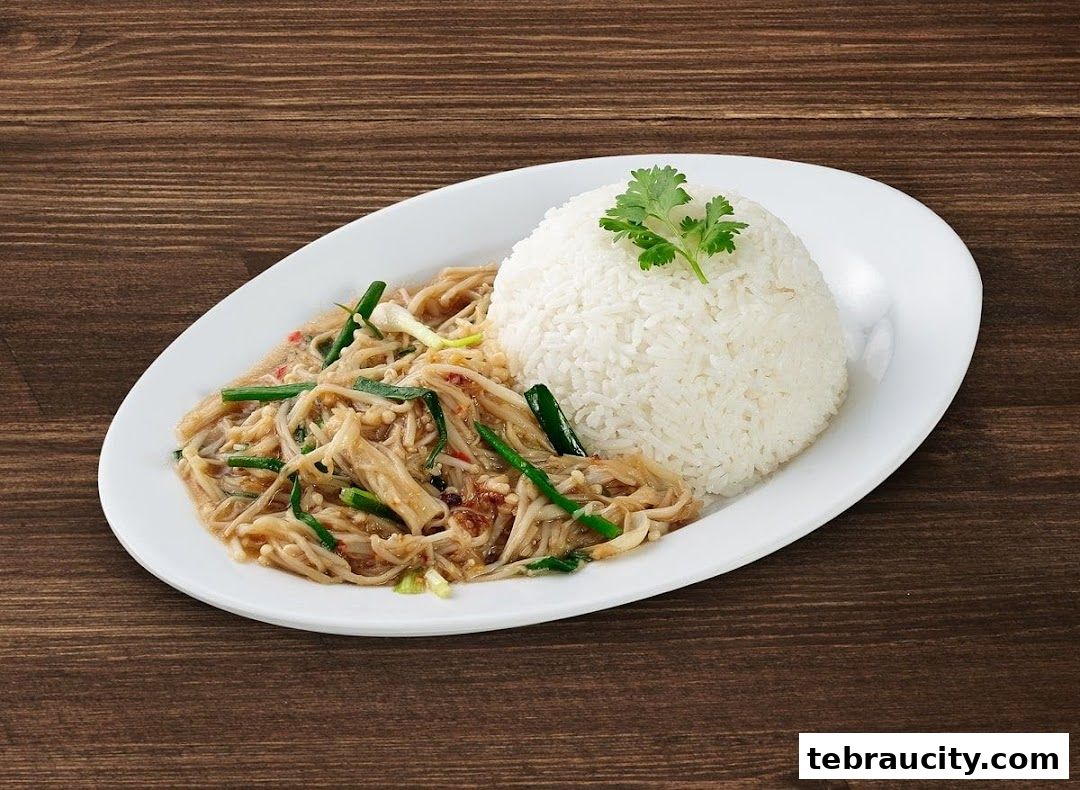 A plate of stir-fried enoki mushrooms with rice, garnished with cilantro.