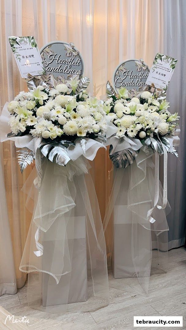Two elegant white floral arrangements with 'Heartfelt Condolences' signs on stands.