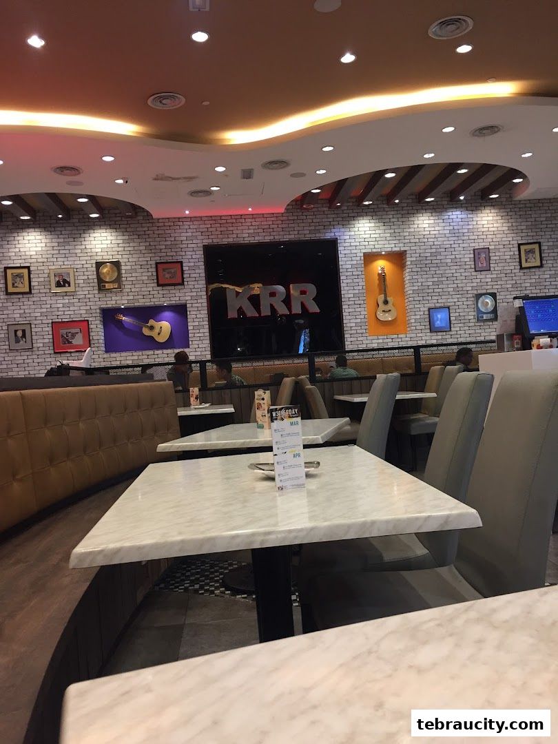 Interior of a Kenny Rogers Roasters restaurant with tables, chairs, and wall decor.