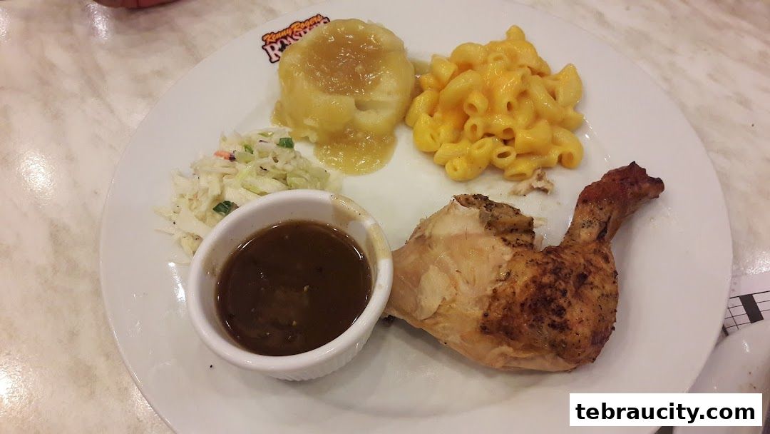 A plate of roasted chicken with mashed potatoes, macaroni and cheese, coleslaw, and gravy.