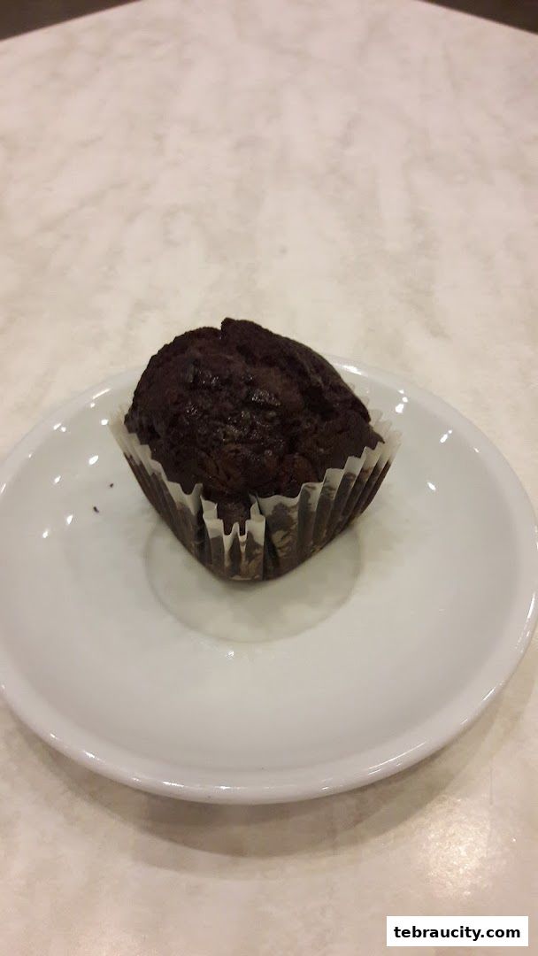 A close-up shot of a chocolate muffin on a white plate.