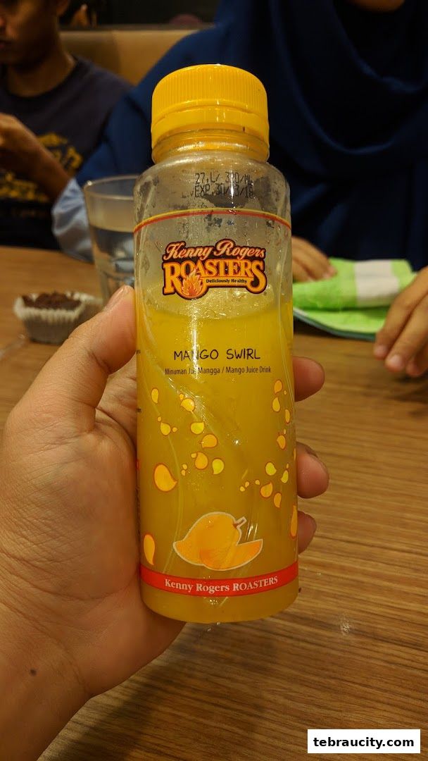 A hand holds a bottle of Kenny Rogers Roasters Mango Swirl juice drink.