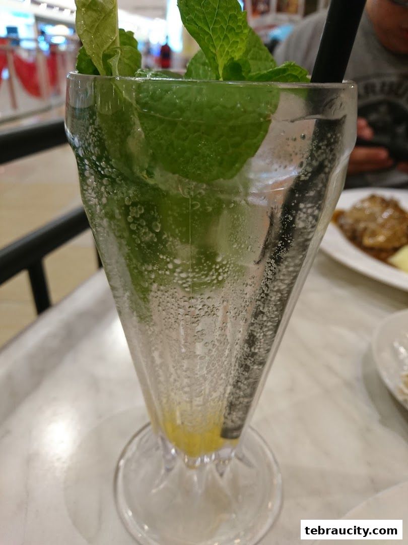 A refreshing drink with mint and lemon, served in a tall glass with a straw.