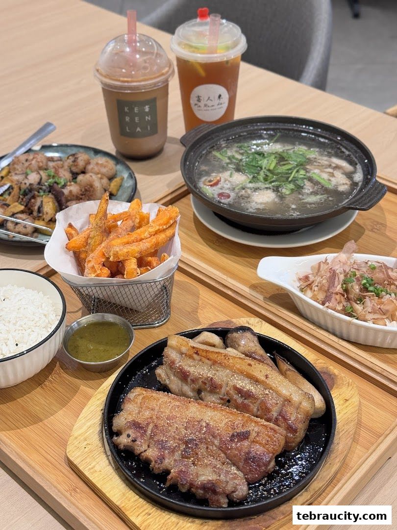 A table laden with various dishes including roasted pork belly, sweet potato fries, soup, and drinks.