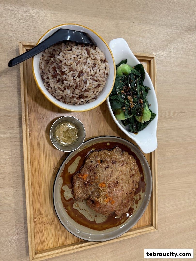 A delicious meal featuring brown rice, stir-fried greens, and a savory meat patty with sauce.