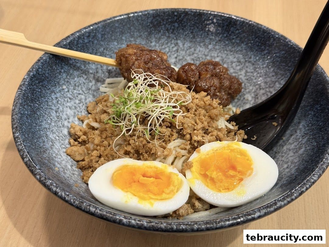 A bowl of noodles topped with minced meat, meatballs, and a soft-boiled egg.
