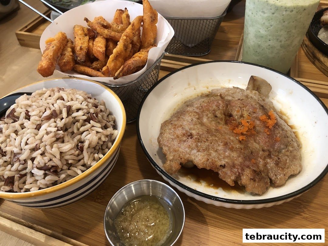 A delicious meal featuring rice, fried sweet potato fries, and a pork chop with sauce.