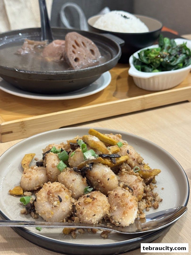 A close-up of a delicious meal featuring fried scallops, soup with lotus root, and a side of greens.