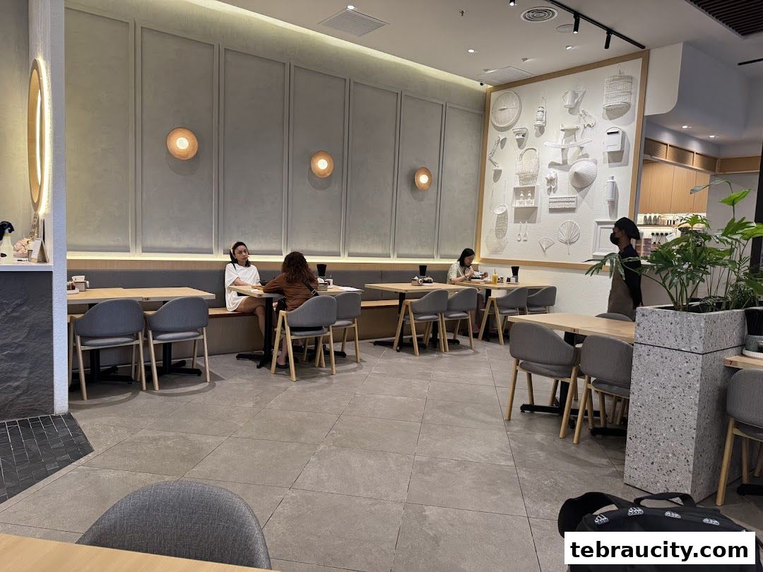 Interior of a modern restaurant with customers dining and a staff member.