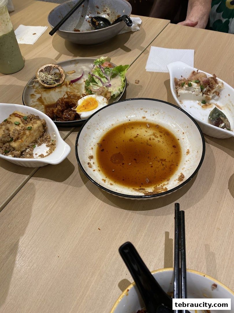 A table with dirty plates, cutlery, and leftover food after a meal.