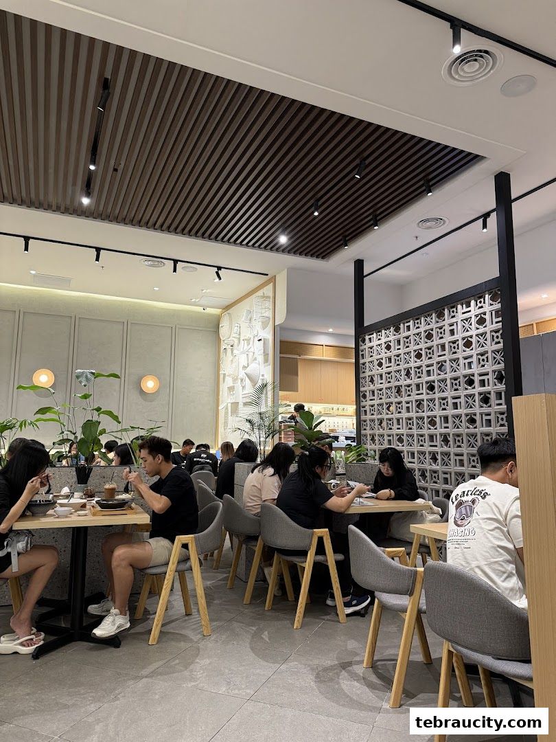 Diners enjoying meals at tables inside a modern restaurant with stylish decor and lighting.