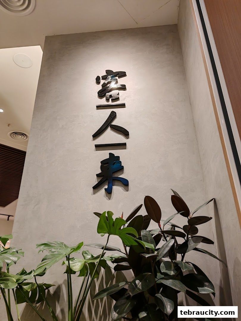 A wall with Chinese characters and lush green plants in front of it.