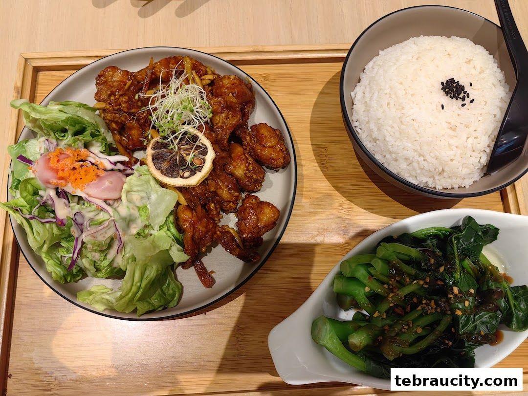 A delicious meal featuring fried chicken, salad, rice, and stir-fried vegetables.