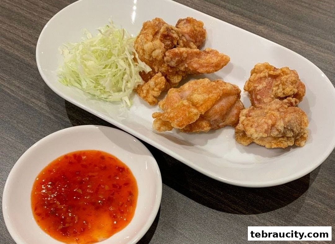 Crispy fried chicken pieces served with shredded cabbage and a side of sweet chili sauce.