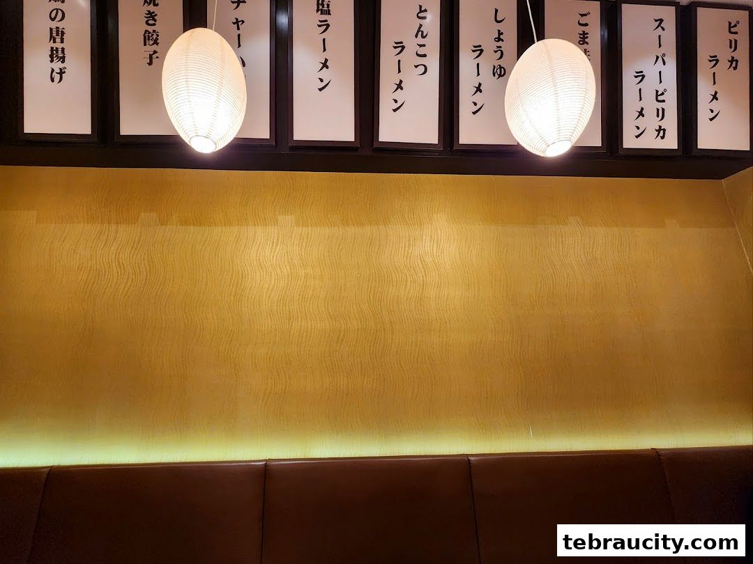 A wall with Japanese menu items and hanging lanterns in a restaurant.