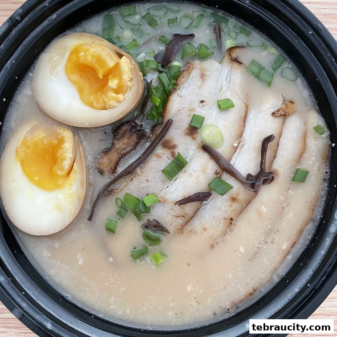 A close-up shot of a delicious bowl of ramen with pork, eggs, and green onions.