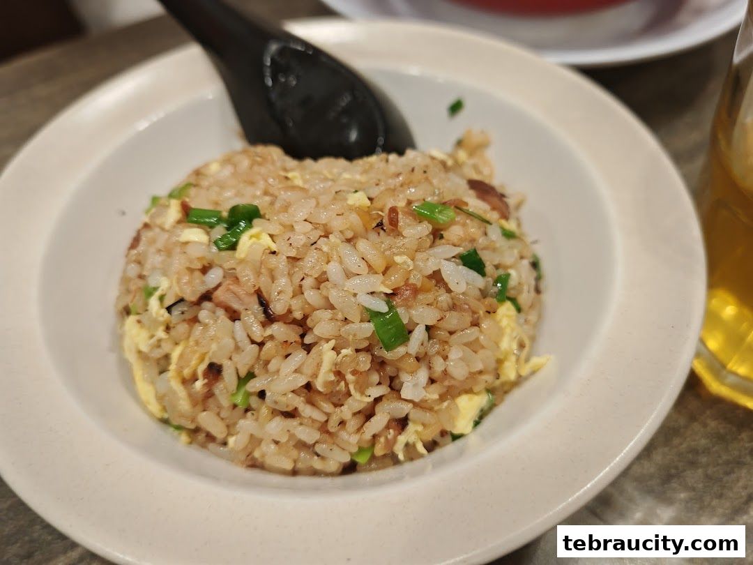A close-up shot of a bowl of fried rice with egg and green onions.