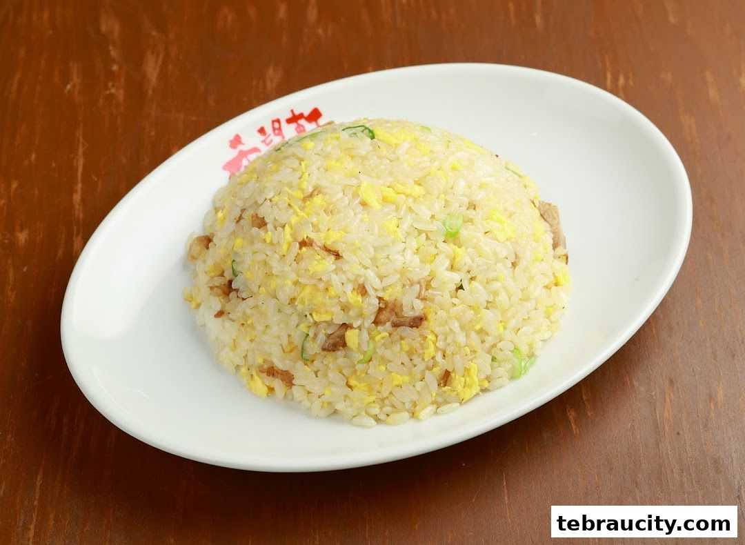 A plate of delicious fried rice with egg and green onions on a wooden table.