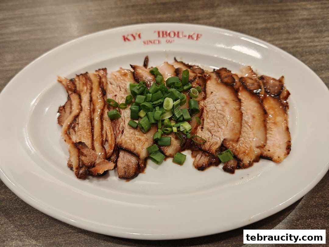 A plate of sliced char siu pork, garnished with chopped green onions.