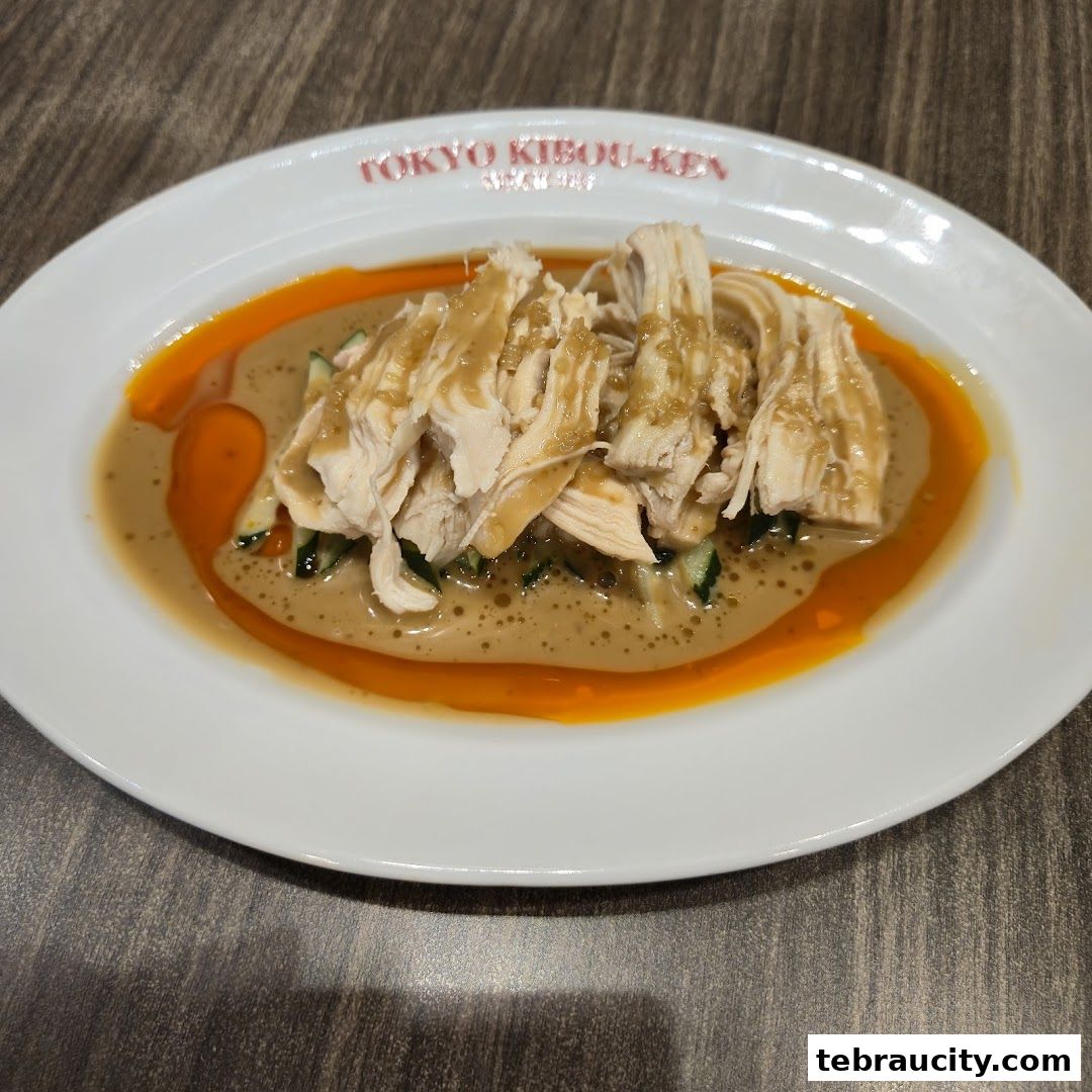 A plate of shredded chicken with cucumber and a creamy sauce, garnished with chili oil.