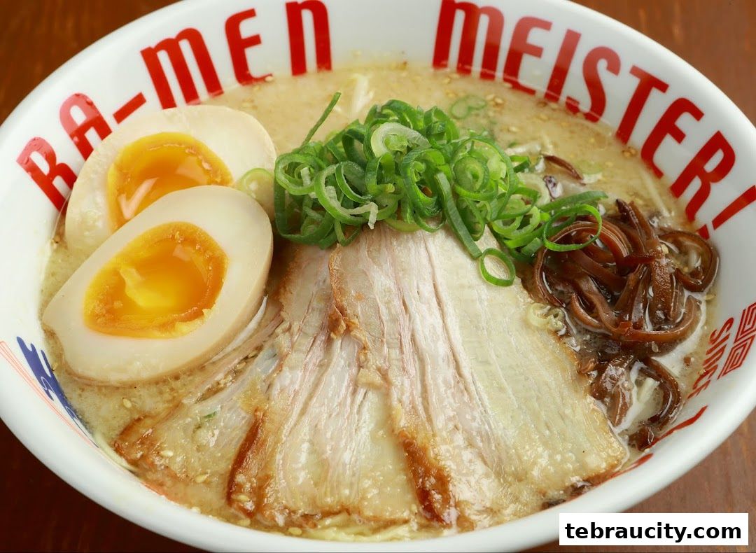 A close-up of a delicious bowl of ramen with chashu pork, soft-boiled eggs, and green onions.
