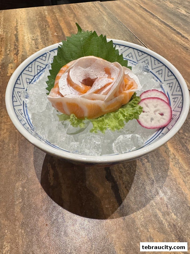 A beautifully presented salmon sashimi dish arranged like a rose on ice.