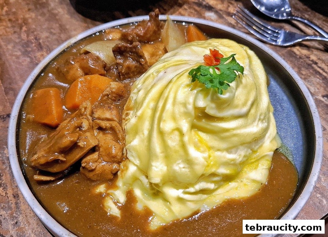 A close-up of a Japanese curry dish with fluffy omelet and tender chicken.